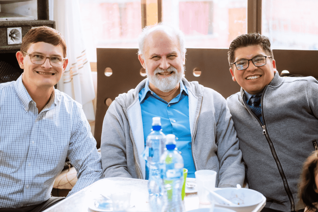 Three men smiling at a table