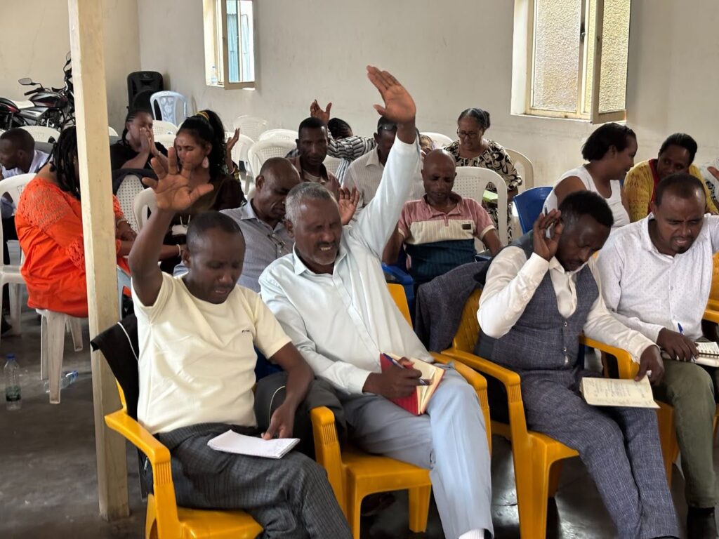 People sitting in chairs and raising hands