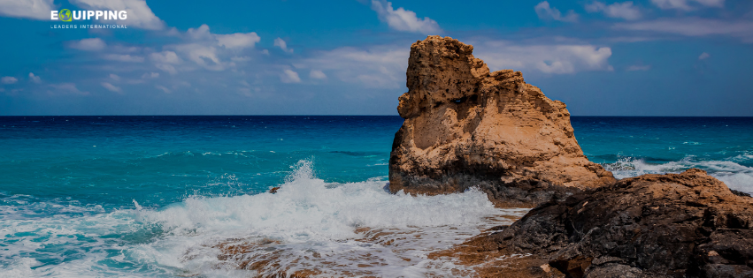A rock surrounded by water and a wave